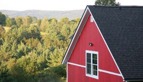 A two story red house with white trim by allied building in central vermont